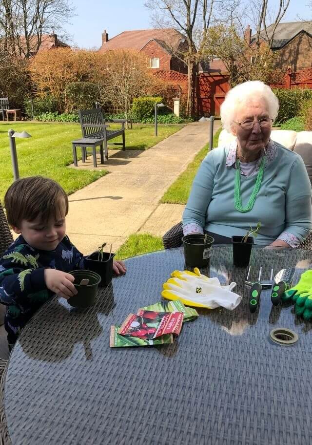 Blossomfield Grange resident Sylvia teachers her great grandson, Jack, how to plant seeds.